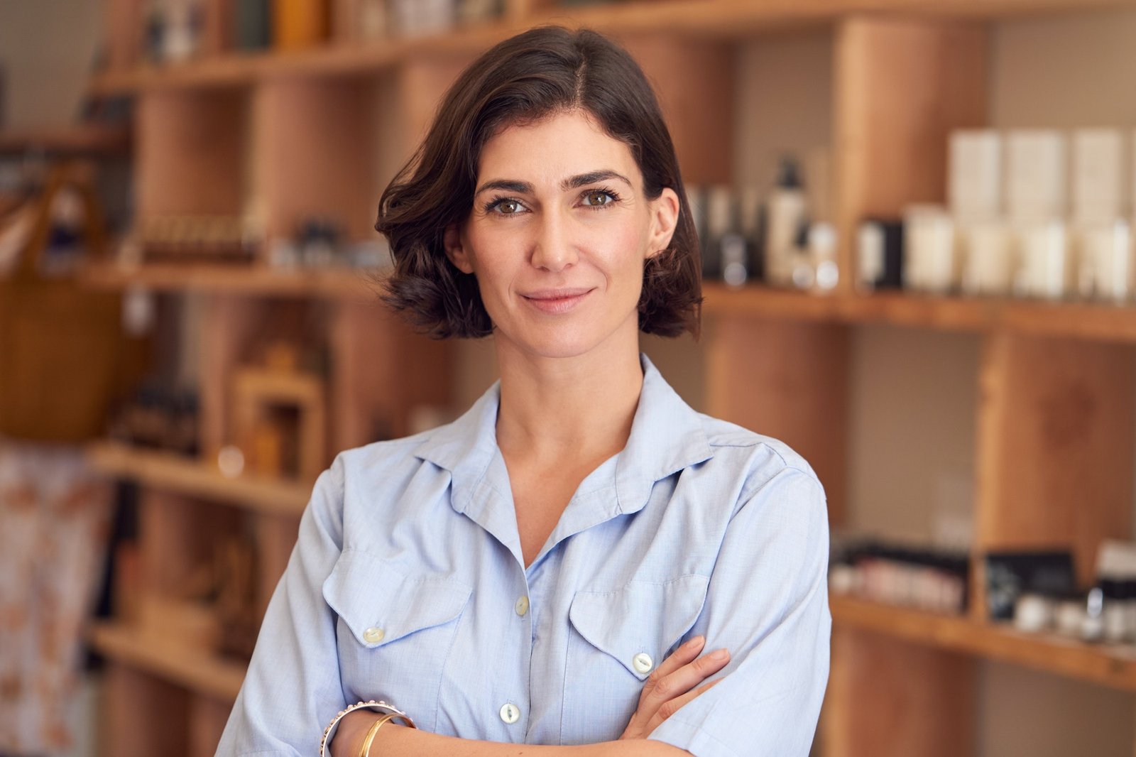 Portrait Of Female Owner Of Gift Store Standing In Front Of Shelves With Cosmetics And Candles